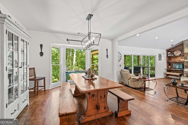 dining space featuring hardwood / wood-style flooring, an inviting chandelier, and lofted ceiling