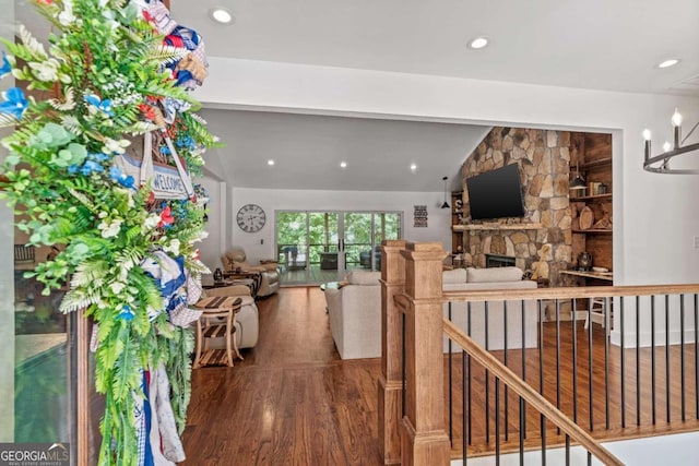 unfurnished living room with hardwood / wood-style flooring, a stone fireplace, and vaulted ceiling