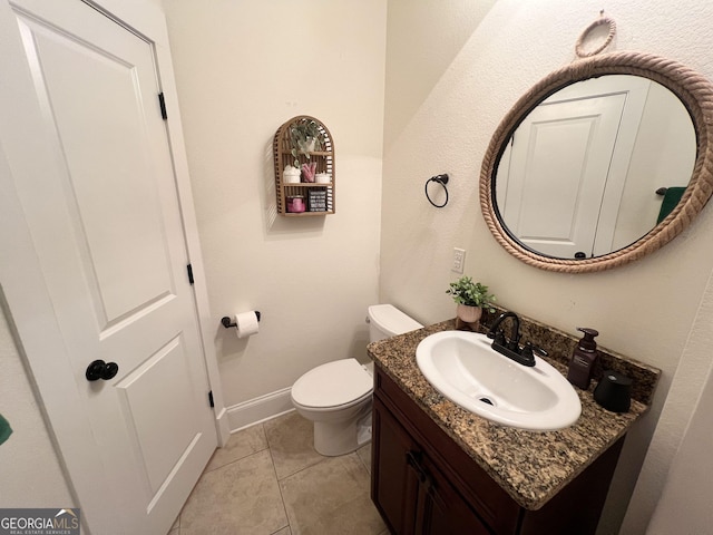 half bathroom featuring tile patterned flooring, baseboards, vanity, and toilet