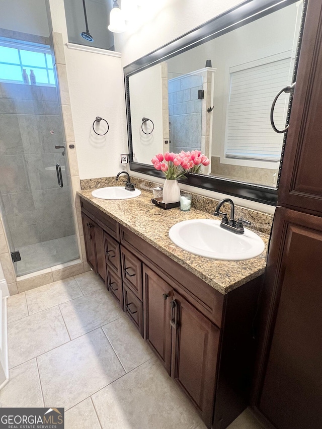 full bathroom featuring double vanity, a stall shower, tile patterned flooring, and a sink