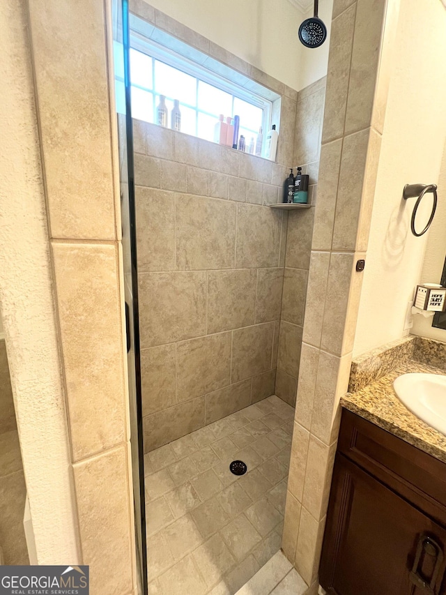 full bathroom with a tile shower and vanity