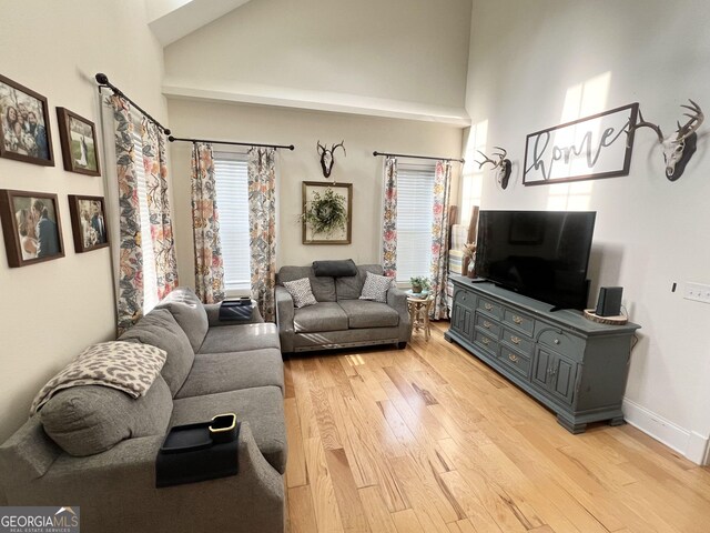 living area featuring plenty of natural light, light wood-style flooring, and high vaulted ceiling