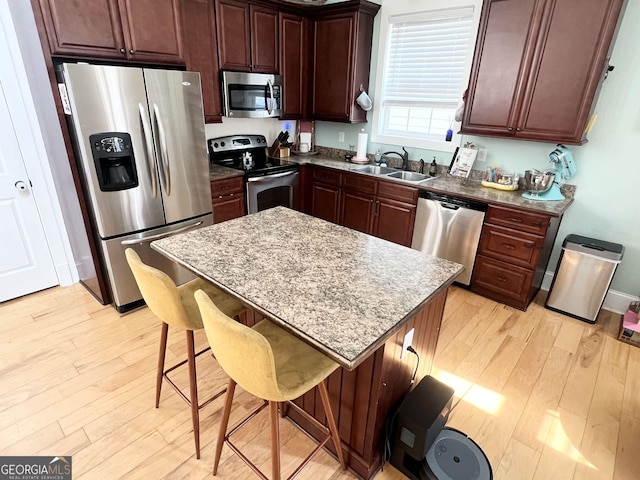 kitchen with stainless steel appliances, a breakfast bar, a sink, and light wood-style floors