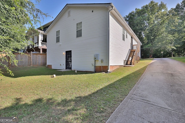 view of side of property with a balcony and a lawn