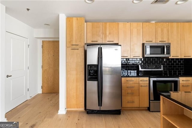 kitchen with decorative backsplash, appliances with stainless steel finishes, light brown cabinets, and light hardwood / wood-style floors