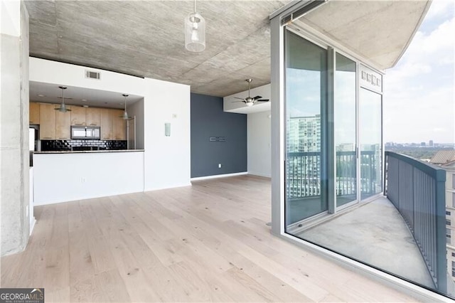 interior space with a wall of windows, ceiling fan, and light wood-type flooring