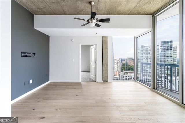 empty room featuring a wealth of natural light, light hardwood / wood-style flooring, and ceiling fan