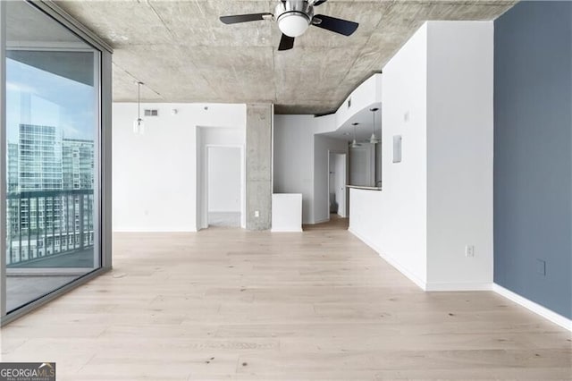 unfurnished room with ceiling fan, a wall of windows, and light hardwood / wood-style flooring