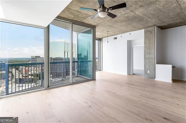 spare room with a wall of windows, hardwood / wood-style flooring, and plenty of natural light