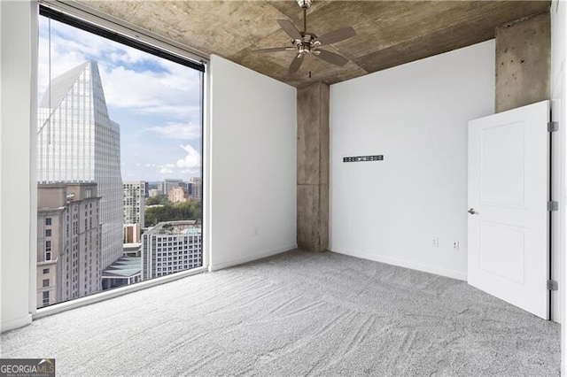 carpeted spare room featuring ceiling fan and a wall of windows