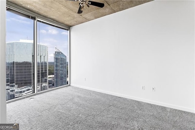 spare room with carpet, a wall of windows, and ceiling fan