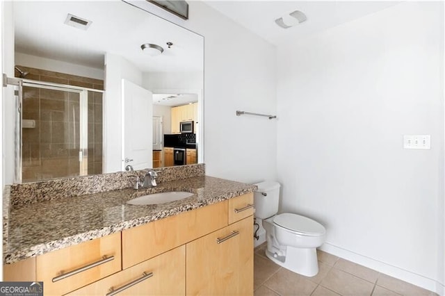 bathroom featuring toilet, vanity, tile patterned floors, and walk in shower