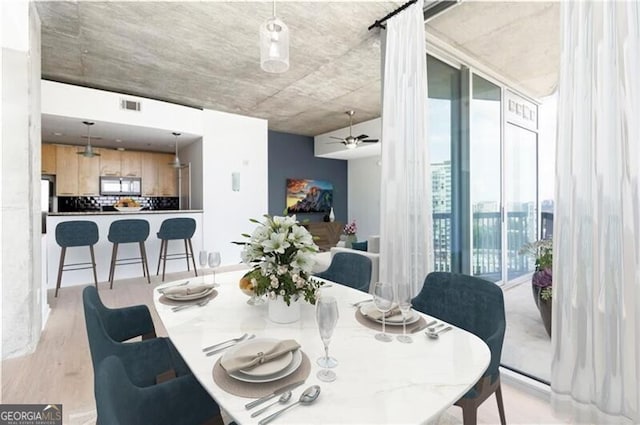 dining space featuring a wall of windows, light hardwood / wood-style flooring, and ceiling fan