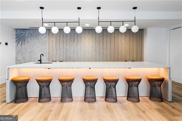 kitchen with a kitchen breakfast bar, hanging light fixtures, and light hardwood / wood-style floors