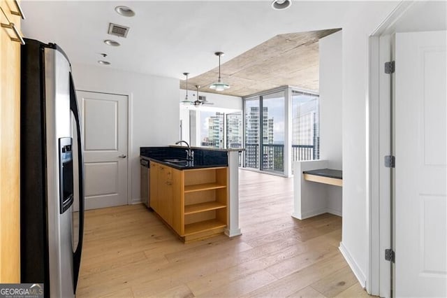 kitchen with sink, decorative light fixtures, light hardwood / wood-style floors, kitchen peninsula, and stainless steel appliances