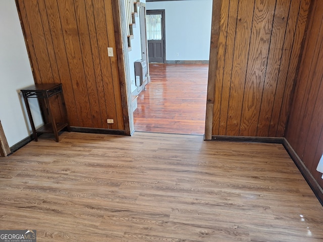 hall with hardwood / wood-style flooring, wooden walls, and heating unit