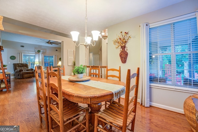 dining room featuring ceiling fan with notable chandelier and wood-type flooring