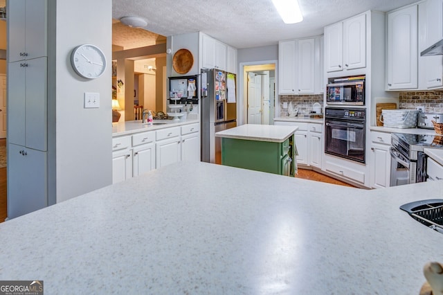 kitchen featuring white cabinetry, appliances with stainless steel finishes, decorative backsplash, and a textured ceiling