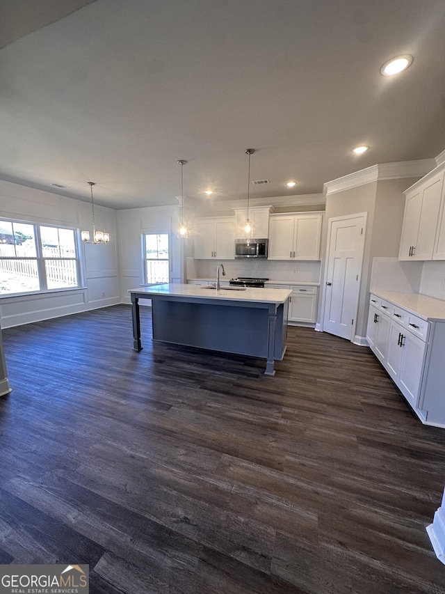 kitchen with white cabinets, dark hardwood / wood-style flooring, an island with sink, and stainless steel appliances