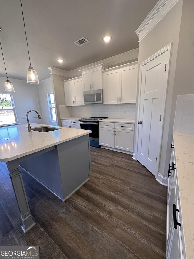 kitchen featuring a center island with sink, appliances with stainless steel finishes, decorative light fixtures, white cabinets, and sink