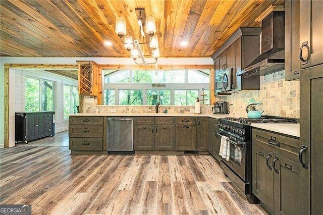 kitchen featuring wall chimney exhaust hood, backsplash, appliances with stainless steel finishes, and a healthy amount of sunlight