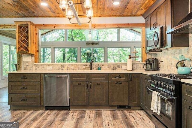 kitchen with light hardwood / wood-style flooring, appliances with stainless steel finishes, wall chimney exhaust hood, and decorative backsplash