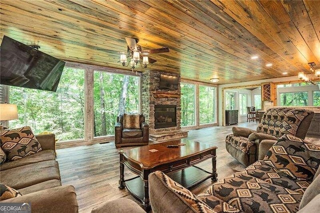 living room with ceiling fan, a stone fireplace, wood-type flooring, and wood ceiling