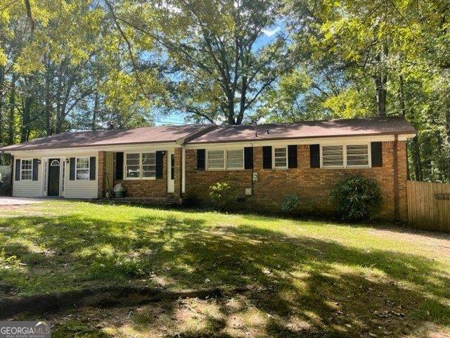 single story home with a front lawn, fence, and brick siding