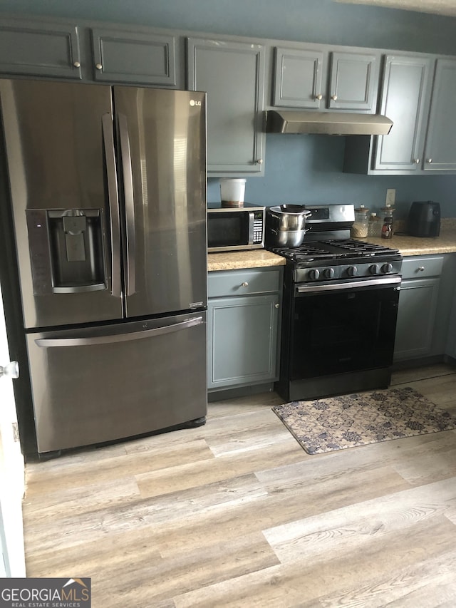 kitchen with gray cabinets, stainless steel appliances, and light wood-type flooring