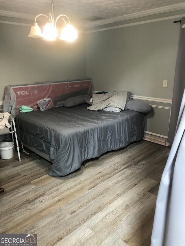 bedroom featuring crown molding, an inviting chandelier, and hardwood / wood-style flooring