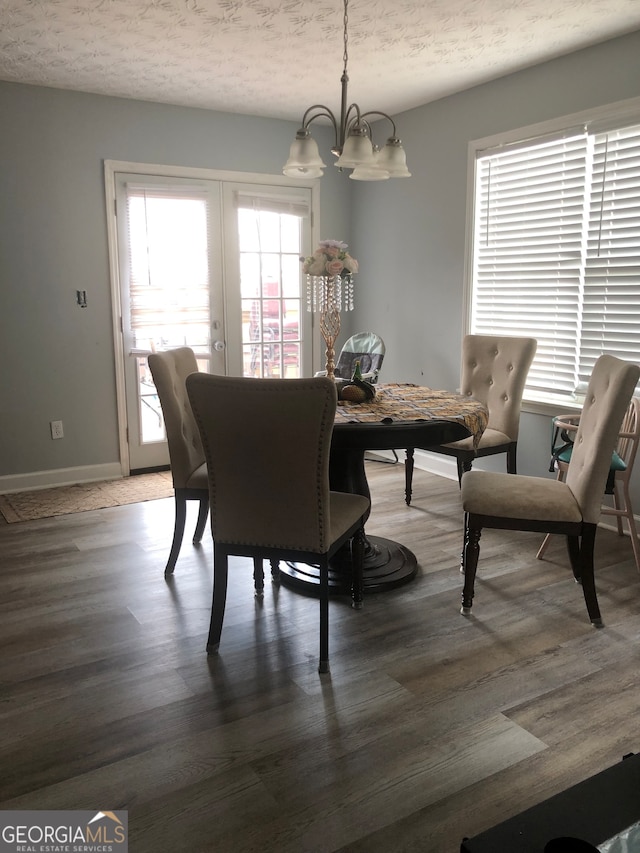 dining room featuring an inviting chandelier, a textured ceiling, plenty of natural light, and dark wood-type flooring