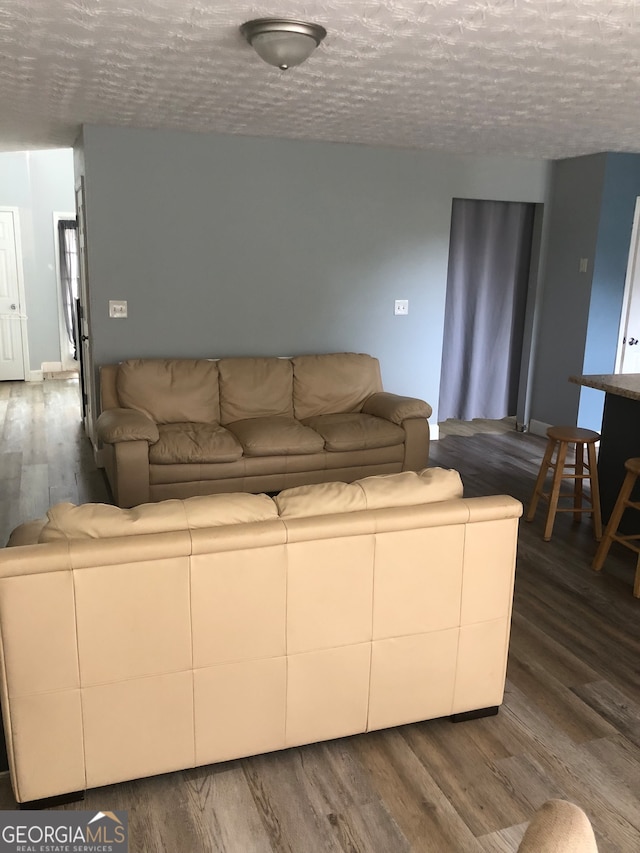 living room with a textured ceiling and dark wood-type flooring