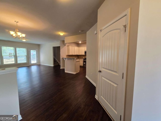 unfurnished living room featuring dark wood-style floors, stairs, baseboards, and an inviting chandelier