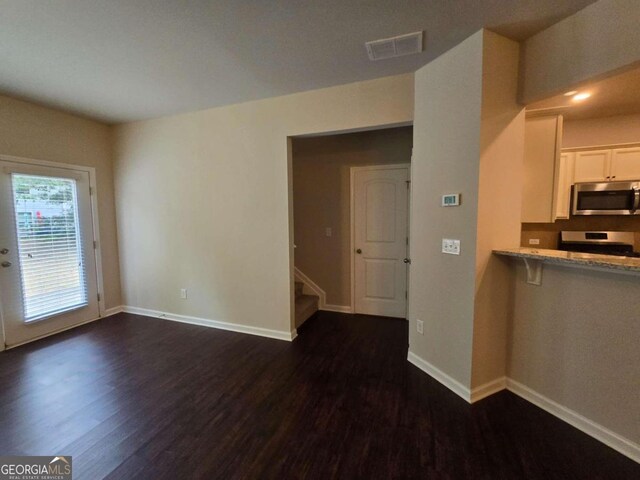 interior space with dark wood-type flooring, visible vents, baseboards, and stairs