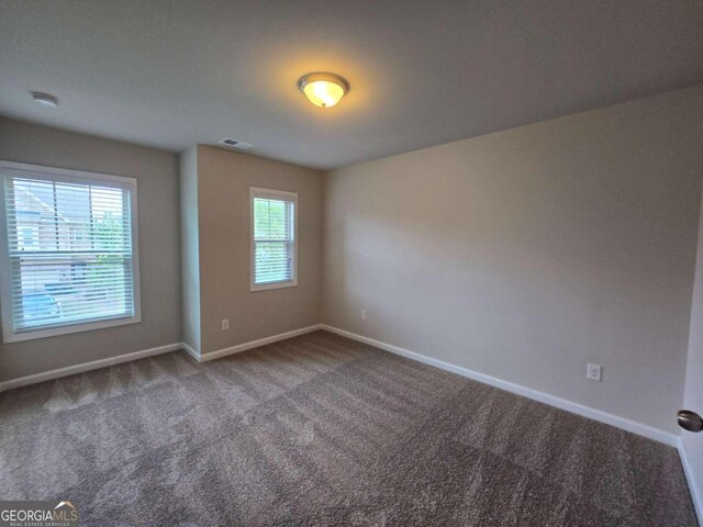 carpeted empty room with visible vents and baseboards