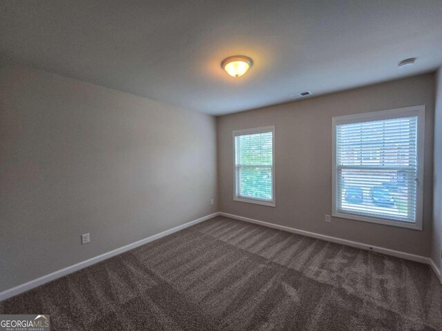 spare room with carpet, baseboards, and visible vents