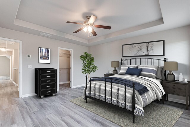 bedroom featuring a walk in closet, a tray ceiling, and a closet