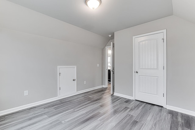 additional living space with hardwood / wood-style floors and lofted ceiling