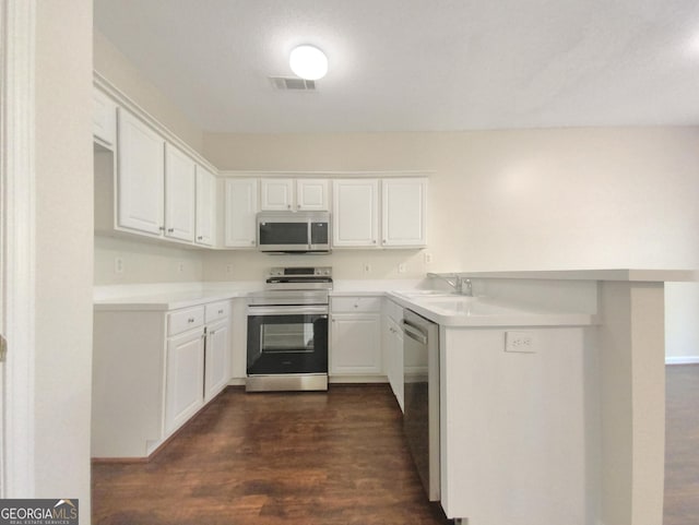 kitchen featuring stainless steel appliances, a sink, white cabinetry, light countertops, and dark wood finished floors