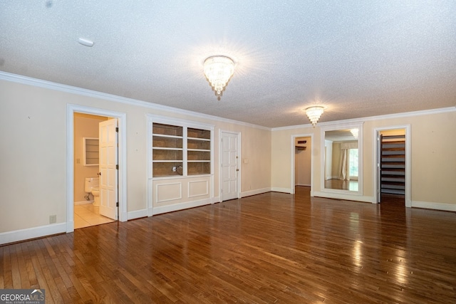 spare room with ornamental molding, built in shelves, a textured ceiling, and hardwood / wood-style floors