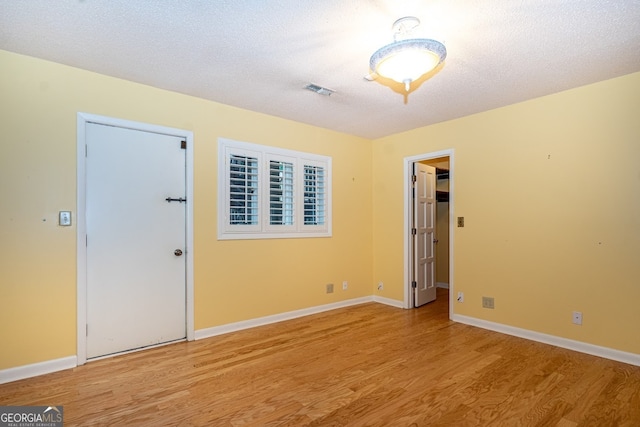 unfurnished room featuring light hardwood / wood-style floors and a textured ceiling