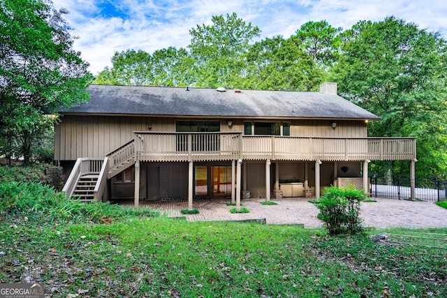 rear view of house featuring a wooden deck, a patio, and a lawn