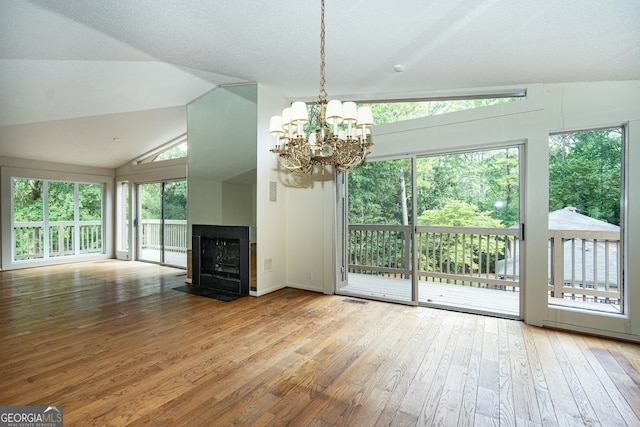 unfurnished living room featuring vaulted ceiling, a textured ceiling, a chandelier, and hardwood / wood-style floors