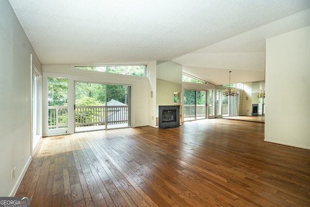 unfurnished living room featuring wood-type flooring, a textured ceiling, a premium fireplace, a chandelier, and vaulted ceiling