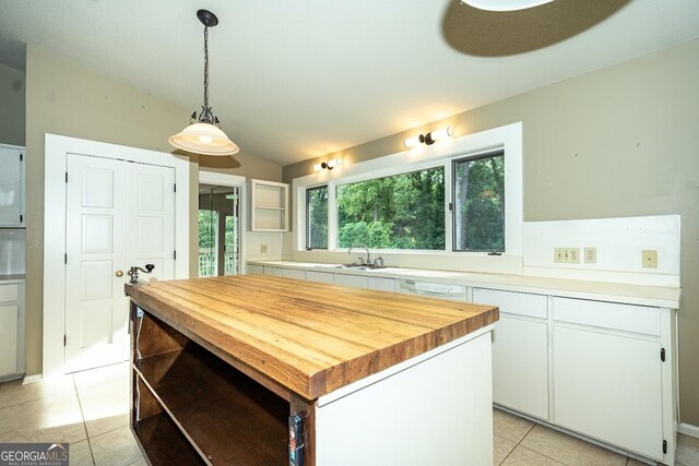 kitchen featuring pendant lighting, a kitchen island, butcher block countertops, white cabinetry, and vaulted ceiling