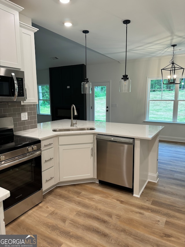 kitchen with sink, white cabinetry, stainless steel appliances, an inviting chandelier, and light wood-type flooring