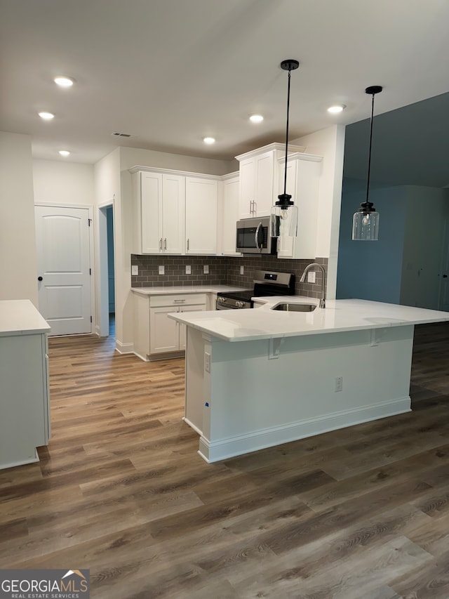 kitchen featuring pendant lighting, appliances with stainless steel finishes, kitchen peninsula, and white cabinetry