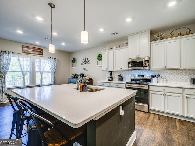 kitchen featuring dark wood-style floors, stainless steel appliances, visible vents, backsplash, and a sink