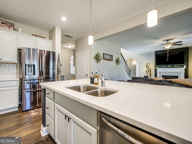 kitchen with arched walkways, stainless steel appliances, a sink, visible vents, and decorative light fixtures