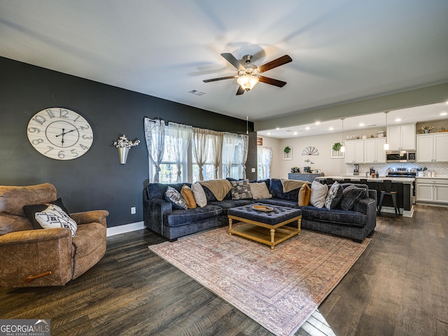 living area with dark wood-style floors, visible vents, baseboards, and a ceiling fan